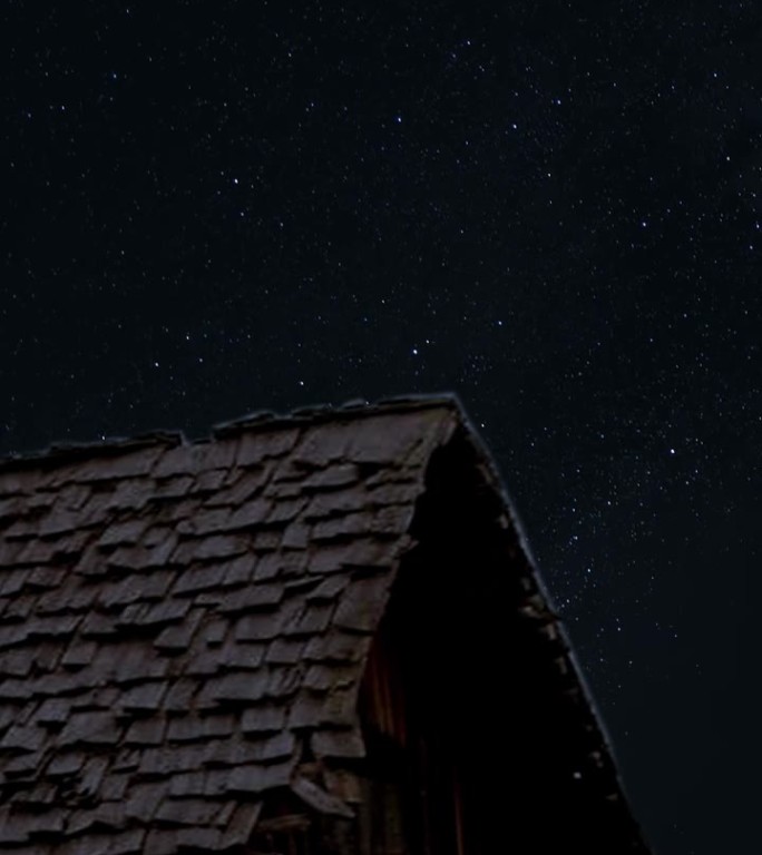 星星移动的夜空在村庄的房子时移星移和星迹与老村庄的房子在前面垂直视频