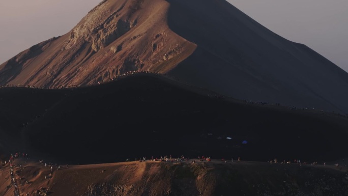 在危地马拉一座冒烟的火山前，无人机从徒步旅行者的视线中倾斜而出