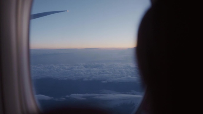 在飞行中，一位女士打开飞机窗户，让光线射入机舱。