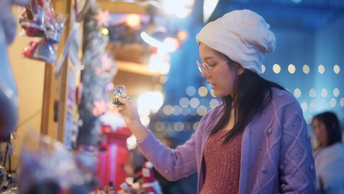 一名怀孕的亚洲年轻女子在圣诞市场为她的朋友挑选圣诞礼物。
