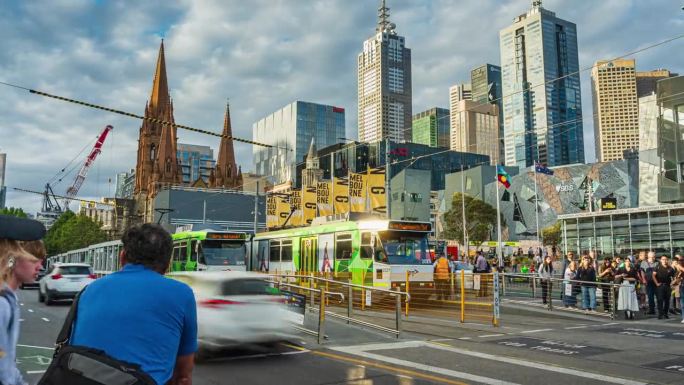 拥挤的通勤者和游客在澳大利亚维多利亚州墨尔本的弗林德斯街火车站与圣保罗大教堂之间行走和穿过马路的时间