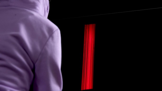 一个穿着淡紫色毛衣的女孩的背影和一个显示字母H的电视屏幕，netflix正在接近特写全屏慢动作视频，