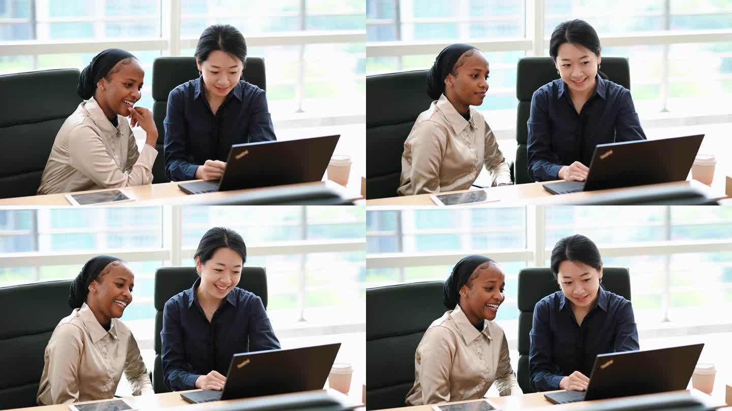 一个非洲女孩和一个中国女孩在学校或办公室里分享。