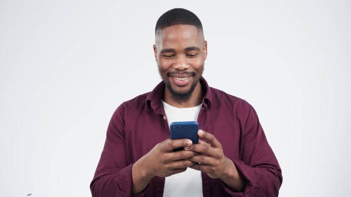 手机、短信和黑人在演播室笑，在灰色背景下发帖子或社交媒体帖子。智能手机、应用程序和非洲小伙在网上为表