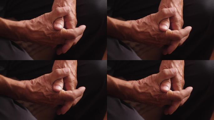 一个退休老人的双臂交叉，一个真正的退休年龄的人，一个80岁老人的皱巴巴的手