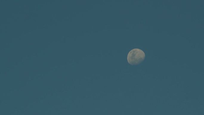 渐弱的黄月亮在蓝色的白天天空