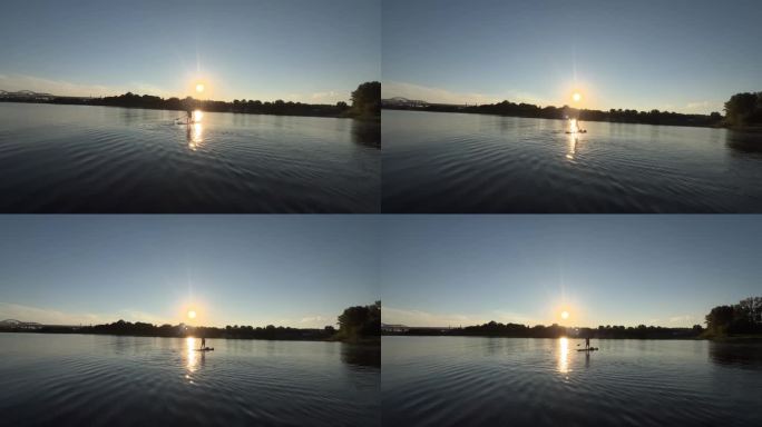 活跃的运动员漂浮在冲浪板与桨平滑的河表面在日落日出景观