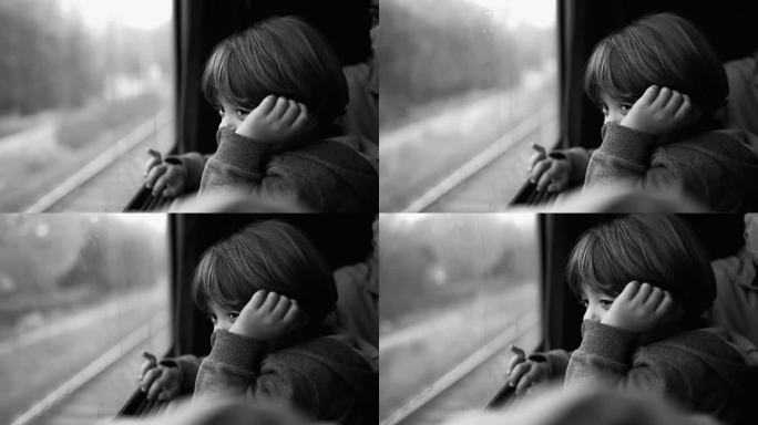 小男孩坐在火车座位上，目不转睛地看着窗外的风景。儿童旅行和白日梦的黑白场景