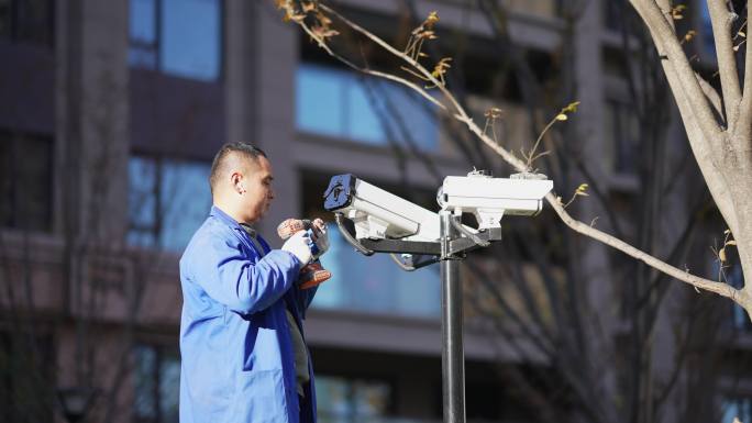 工程师在住宅小区内安装监控安防设备摄像头