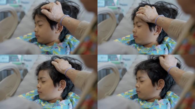 一位亚洲祖母抚摸着一个躺在医院病床上的小男孩的头，她表达了她的爱，并希望他早日康复。