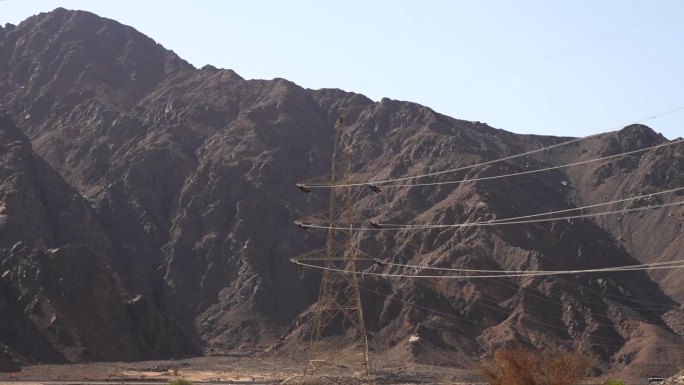 从路过的车窗看，山间沙漠中架起的电力线塔。埃及的电力