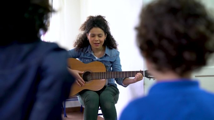开朗的拉丁美洲老师在课堂上和她的学生一起弹吉他，看起来很开心