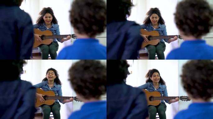 开朗的拉丁美洲老师在课堂上和她的学生一起弹吉他，看起来很开心