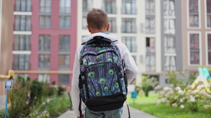 男学生背书包拿课本回家的背影。从教室外面走出来的少年。学校和儿童概念。