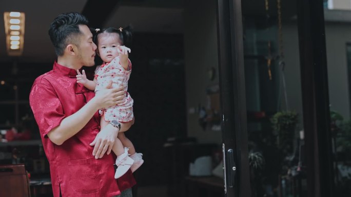 中国新年骄傲的父亲抱着女儿在房子前团聚