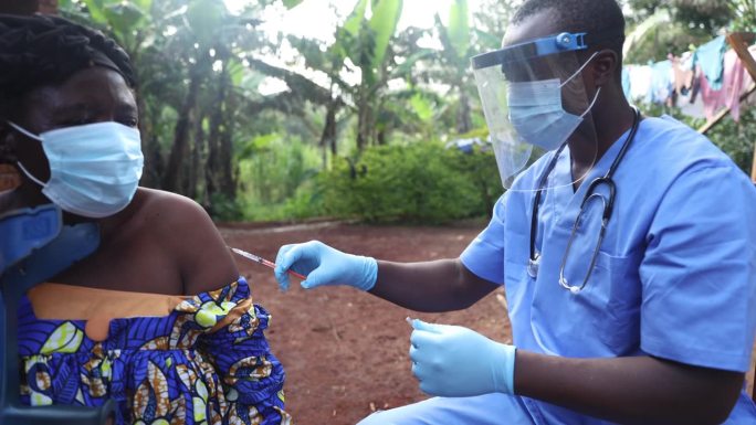 在非洲的一个村庄里，医生用注射器给一位老年病人注射疫苗