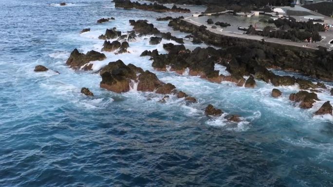 葡萄牙马德拉岛莫尼兹港的火山池，日落时拍摄的悬崖、海洋、天然浴场和房屋的无人机镜头。