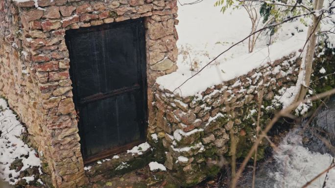 白雪皑皑的老青苔石墙和古城门旁流淌着小溪