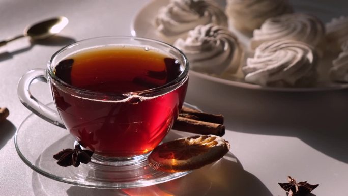 茶装在透明的马克杯或杯子里，白色，浅色背景，棉花糖或蛋白派蛋糕，甜点早餐或早晨的概念