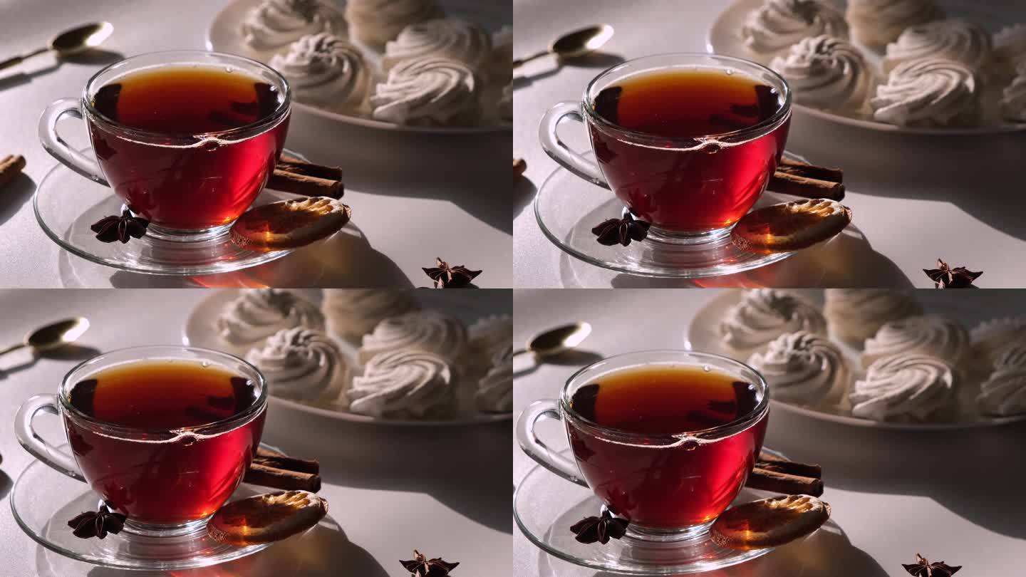 茶装在透明的马克杯或杯子里，白色，浅色背景，棉花糖或蛋白派蛋糕，甜点早餐或早晨的概念