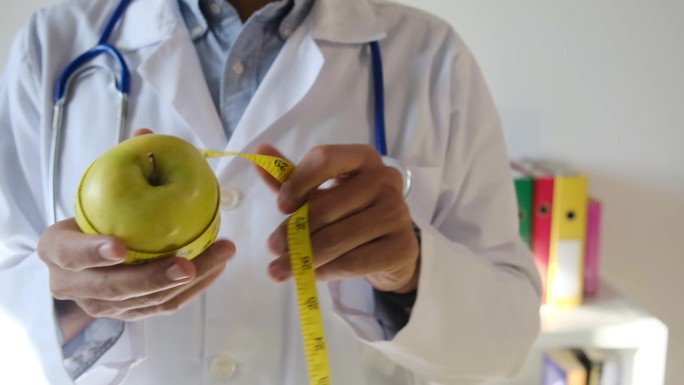 图为，一位营养学家医生正在用卷尺测量苹果