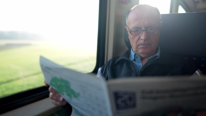 老人在火车上看报纸