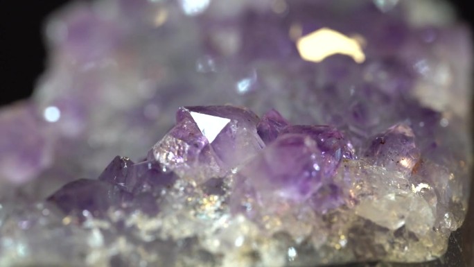 闪亮的紫水晶带有旋转的内含物，近距离观察，石英晶体纹理抽象的背景