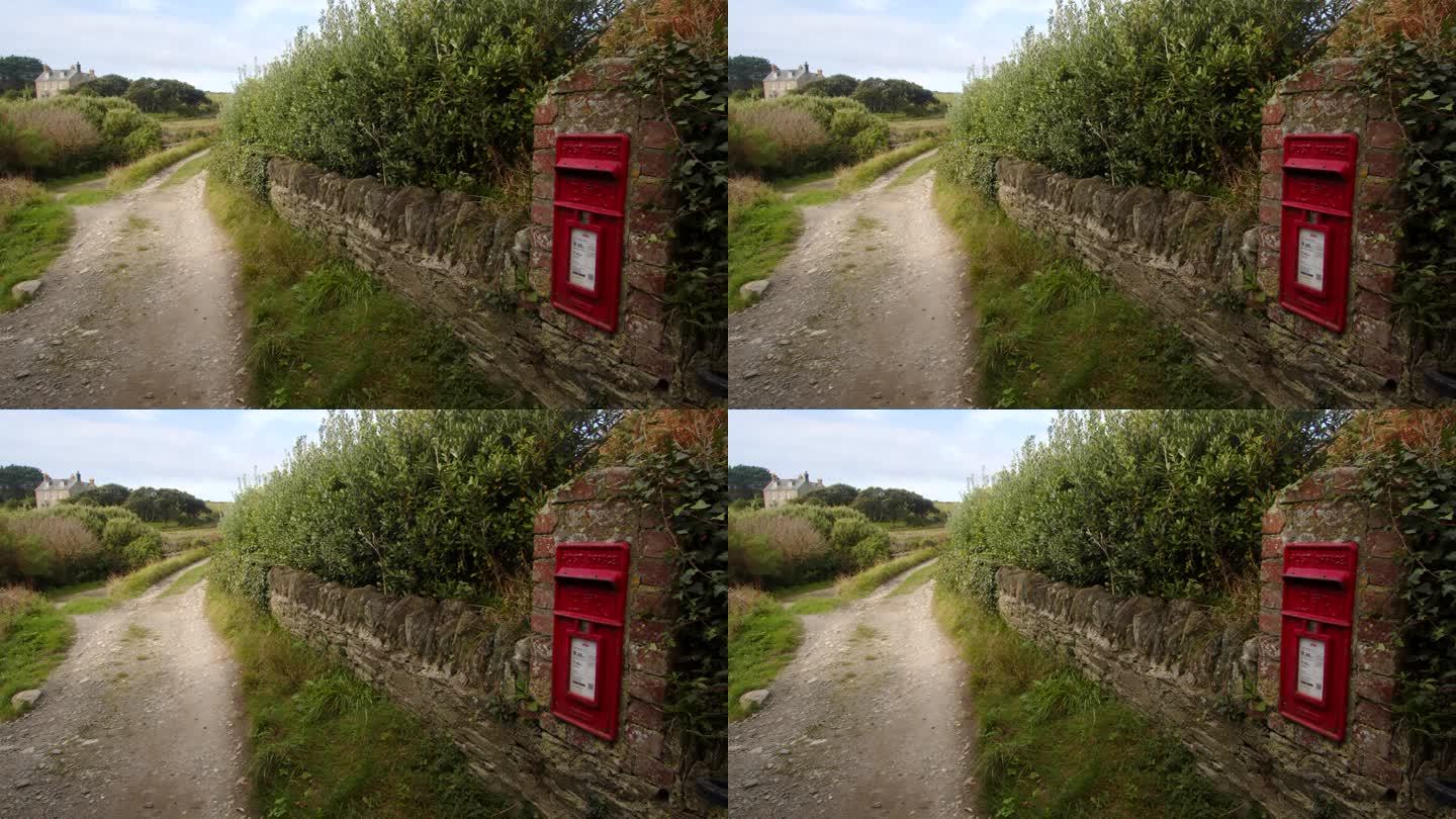 乡村小路的中景，在康沃尔郡的恩尼斯郡贝西湾的石墙上有一个旧邮筒