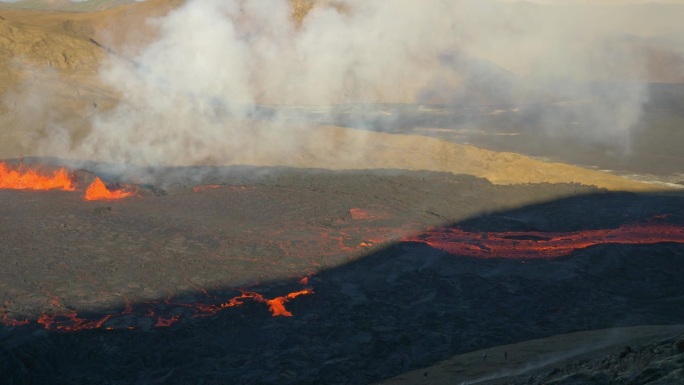 移动鸟瞰图，熔岩从火山口流出。晴天旁边是火山喷发的地方。烟雾和岩浆从火山口冒出来。