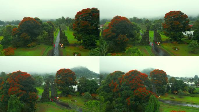 在印度尼西亚的巴厘岛，神秘的Handara门和红色花朵的树和穿红色衣服的女人。电影的地方。无人机航拍