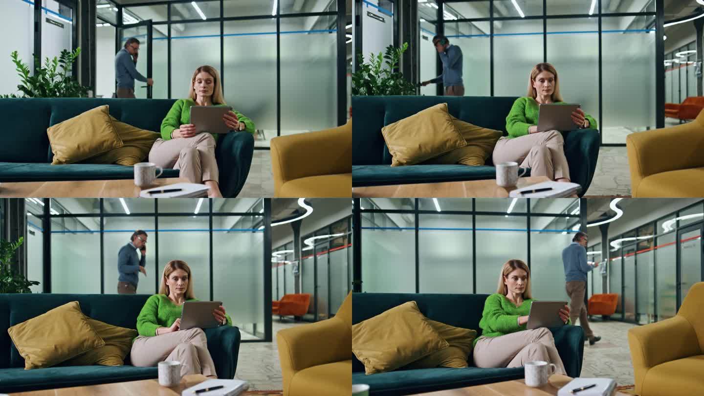 梦幻的女商人在沙发休息室拿着垫子。女老板看着平板电脑屏幕