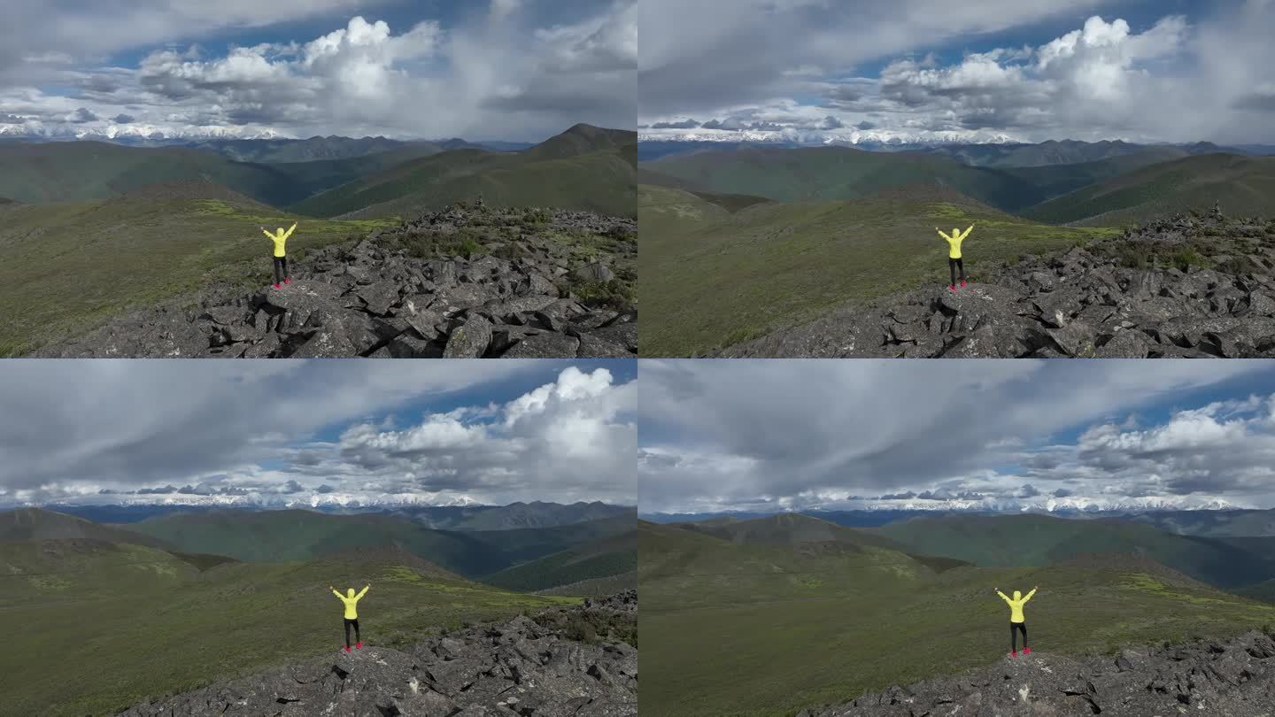 高空女徒步者在高海拔山顶张开双臂的航拍画面