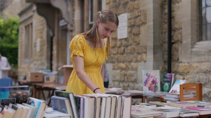 一个十几岁的女孩在慈善街头市场浏览书籍。