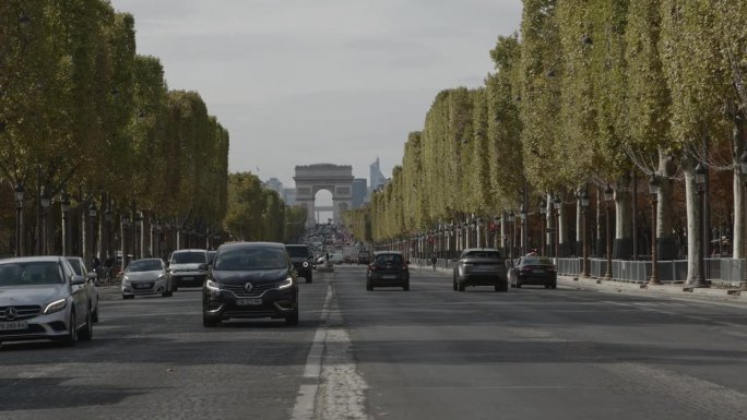 在一个阳光明媚的日子里，法国巴黎的香榭丽舍大道上，汽车、公共汽车和游客川流不息。