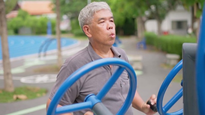 一位年长的亚洲男子在公园的健身站随意锻炼。代表以运动永葆青春，露天健身，身体健康的理念。城市公园户外