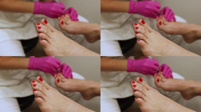 女士在Spa沙龙接受经典的红指甲足疗-角质层油程序。腿部和指甲皮肤护理。足疗程序和SPA。特写，选择