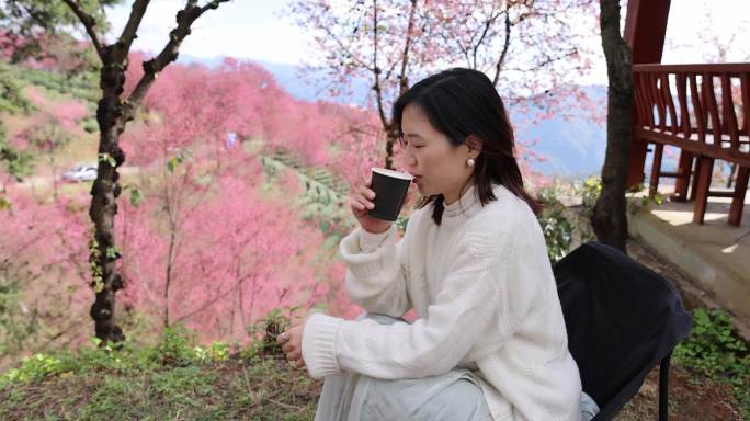在樱花树下喝咖啡的年轻美女唯美慢镜头