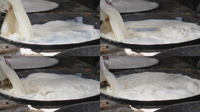 工人将奶油白豆浆倒入热锅中。