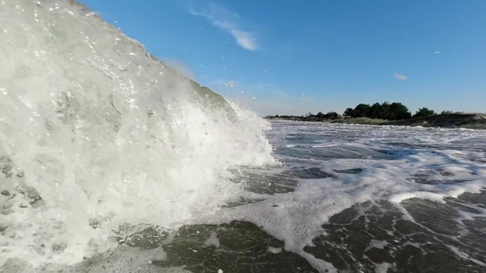 一股海浪冲击着海岸，盖住了摄影师。慢动作