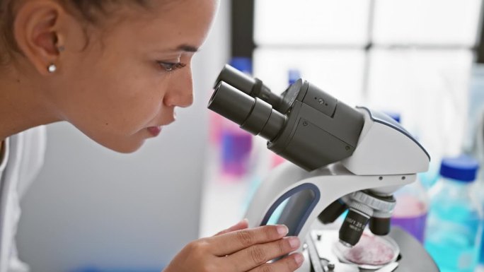 在实验室的中心，一位年轻美丽的西班牙裔女科学家，卷发，热情地专注于她的医学研究，使用显微镜进行细致的