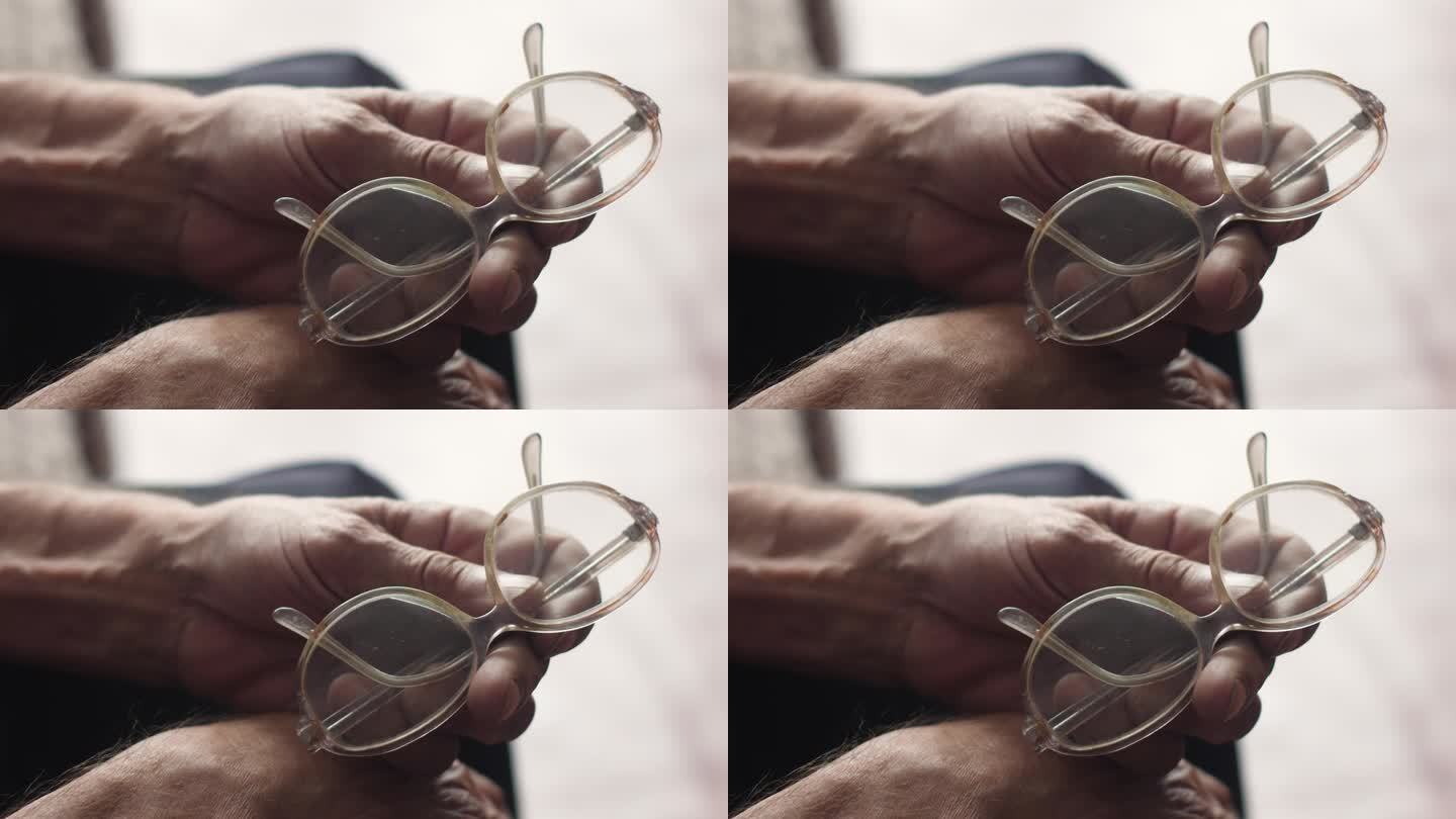 拿着眼镜的退休老人的手。老年人戴眼镜的概念。老年视力减退真正的70岁老人