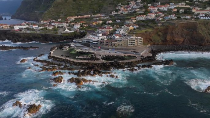葡萄牙马德拉岛莫尼兹港的火山池，拍摄了悬崖、海洋、自然浴场和日落时的房屋。