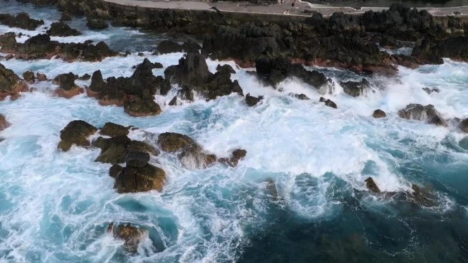 葡萄牙马德拉岛莫尼兹港的火山池，日落时拍摄的悬崖、海洋、天然浴场和房屋的无人机镜头。