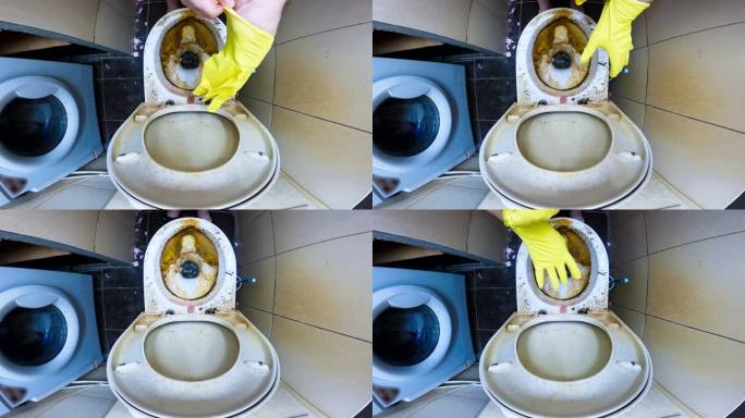 清洁工戴上手套，背景是一个非常脏的厕所。一名男子在肮脏的厕所上戴上黄色乳胶手套。打扫厕所。卫生间的地