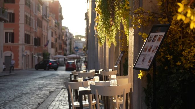 日出时没有客人的意大利餐厅餐桌，背景是柔和的阳光。街上空荡荡的咖啡馆。复古街的户外咖啡馆。