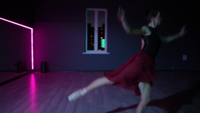 住相机。美丽的芭蕾舞女演员在霓虹灯照亮的黑暗舞蹈大厅里表演优雅的阿拉伯式舞蹈。