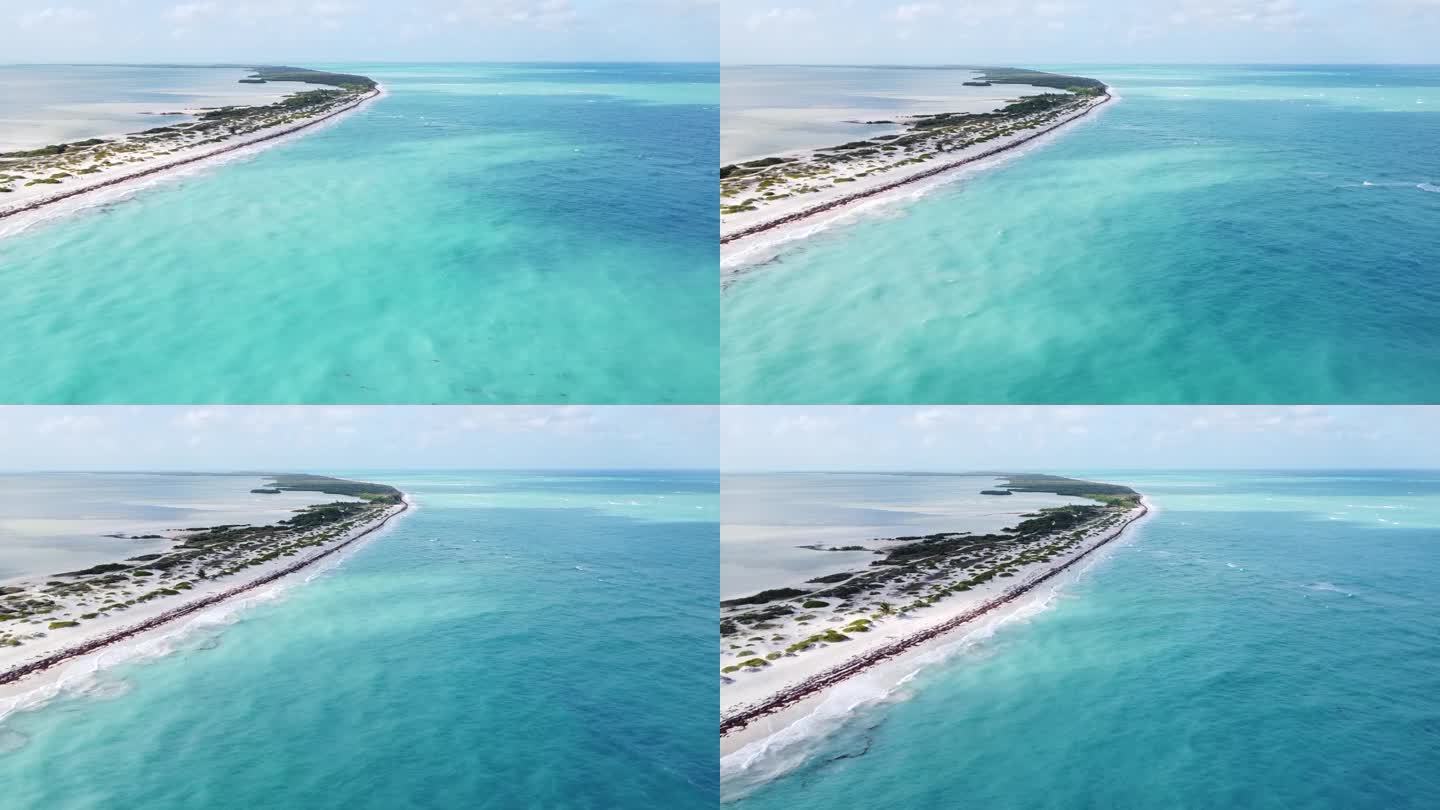 在墨西哥坎昆的布兰卡岛，无人机俯瞰着加勒比海蔚蓝碧绿的海水，而风筝冲浪者正飞过冲刷着白色沙滩的原始蓝