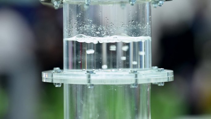 氢气在装满水的塑料瓶中穿过薄膜冒泡，小气泡在液体中形成，慢镜头，缩小画面