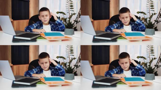 累的小家伙摸着头闭着眼睛，在无线笔记本电脑上上网时头痛不已。身体不适的白种小孩，穿着便装，需要照顾和