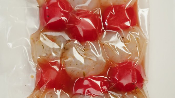 西红柿对虾小吃串在真空塑料袋中准备真空烹调或烧烤，超市准备吃的食物。工作室拍摄，特写，微距，白色背景